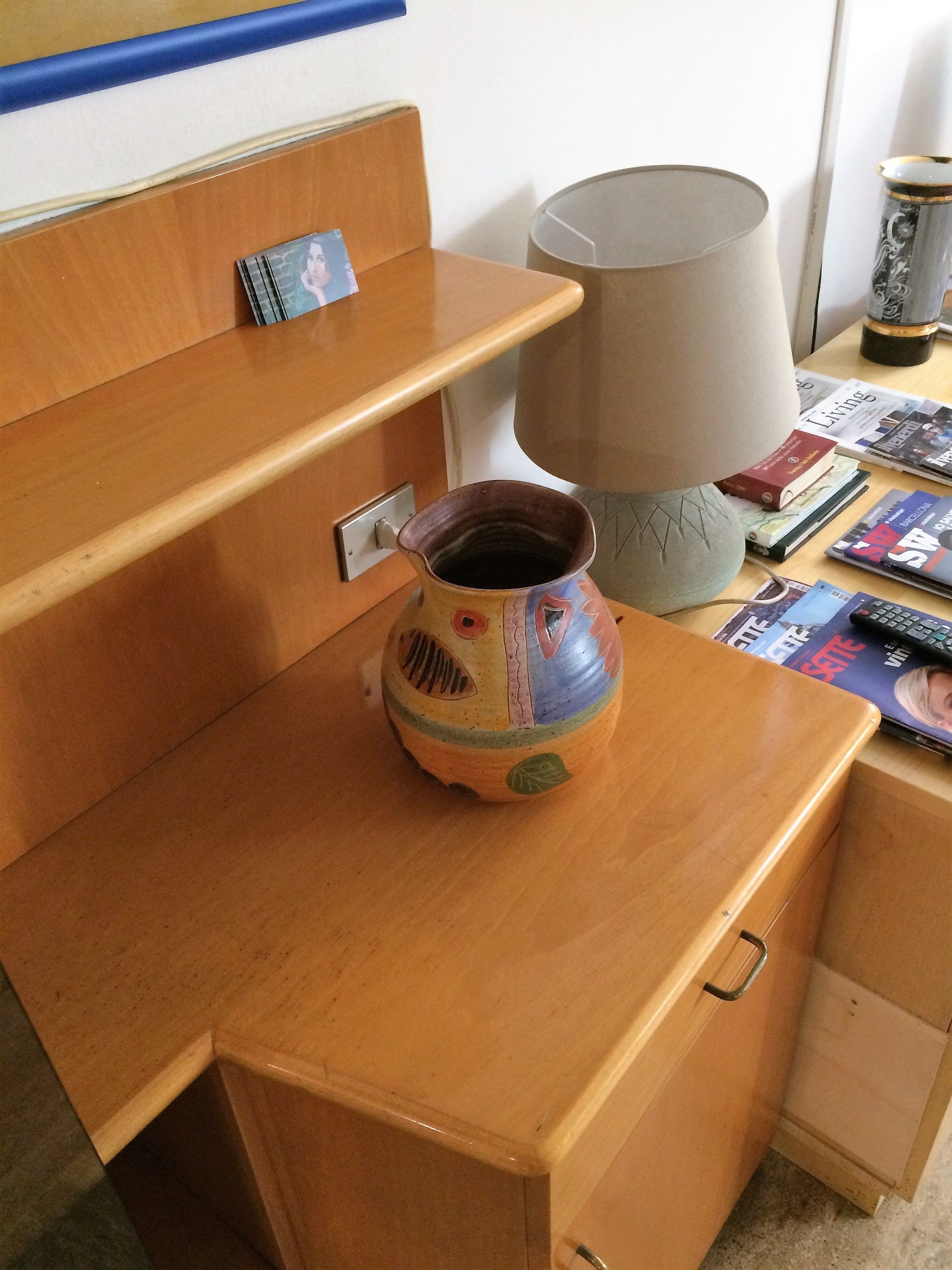 A wooden desk with a ceramic mug, a lamp, and some books.