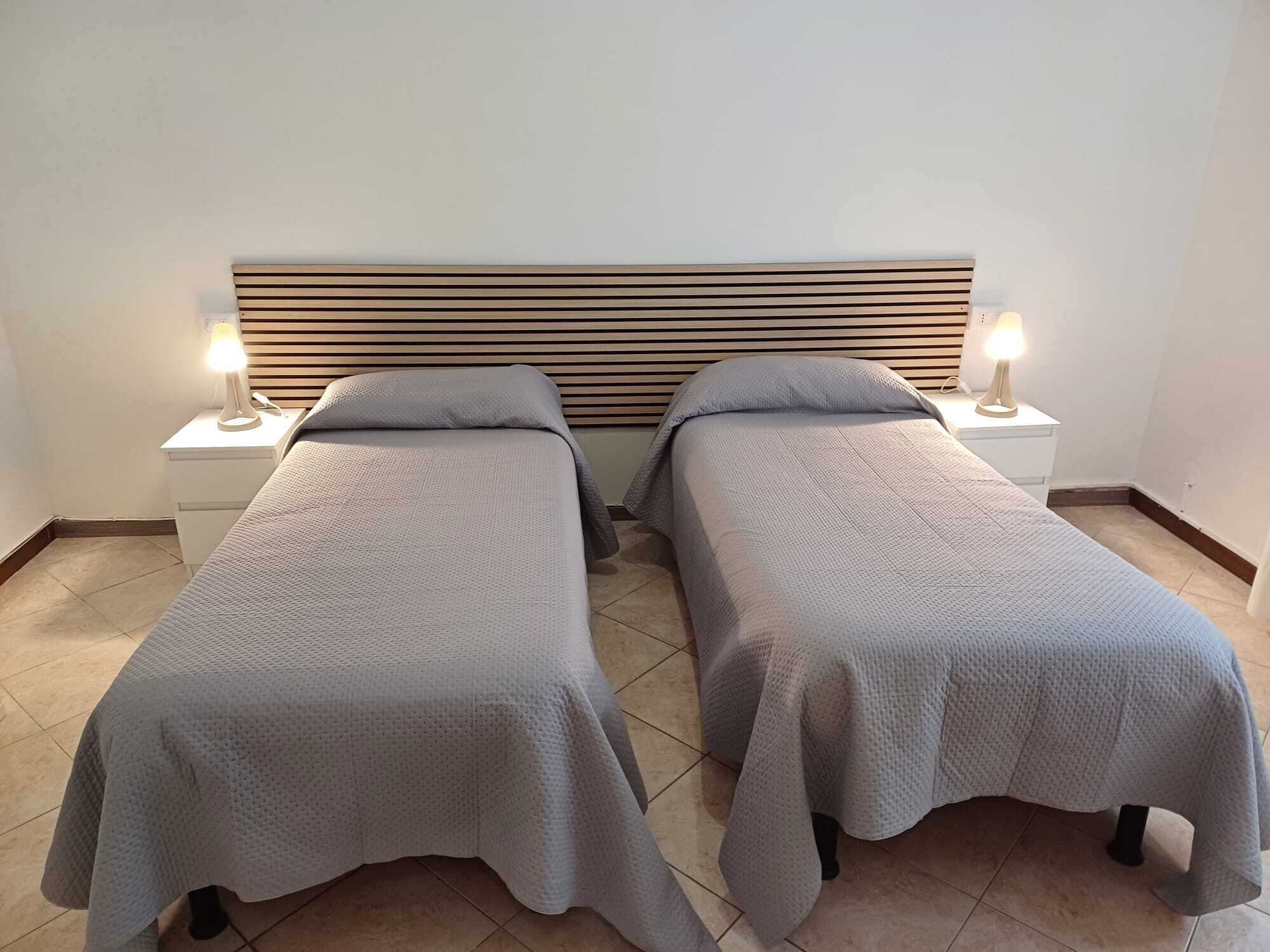 Ein Doppelzimmer mit zwei Einzelbetten, jeweils mit Kopfseiten und Nachttischen.