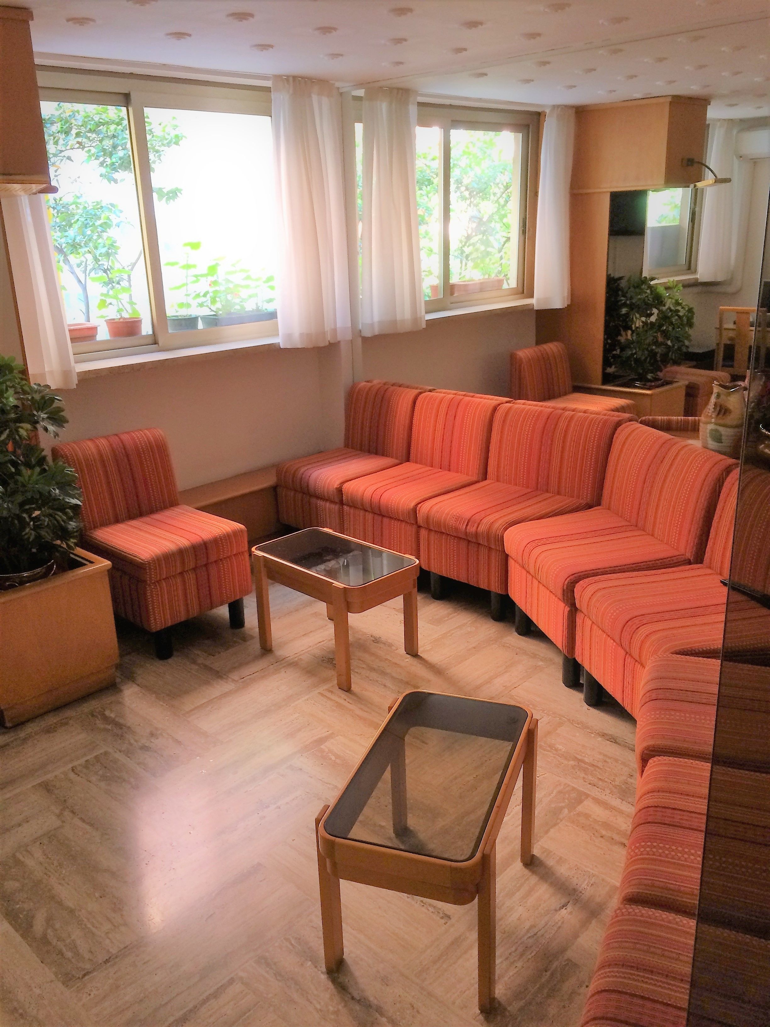 Una sala de estar con un sofá modular, una mesa de centro de vidrio y una planta en maceta.