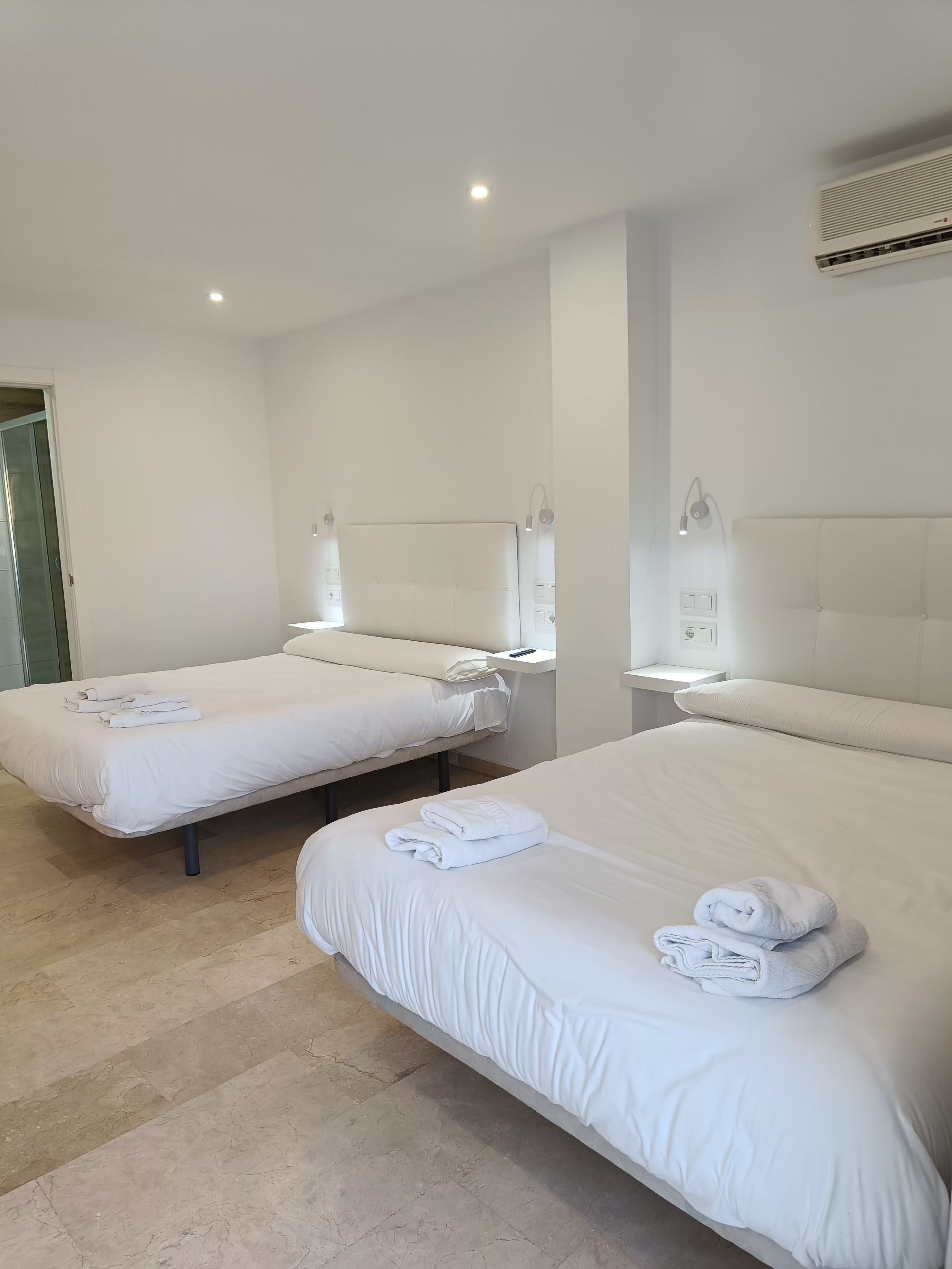 Ein Hotelzimmer mit zwei Betten, jeweils mit Kopfteil und Nachttischen.