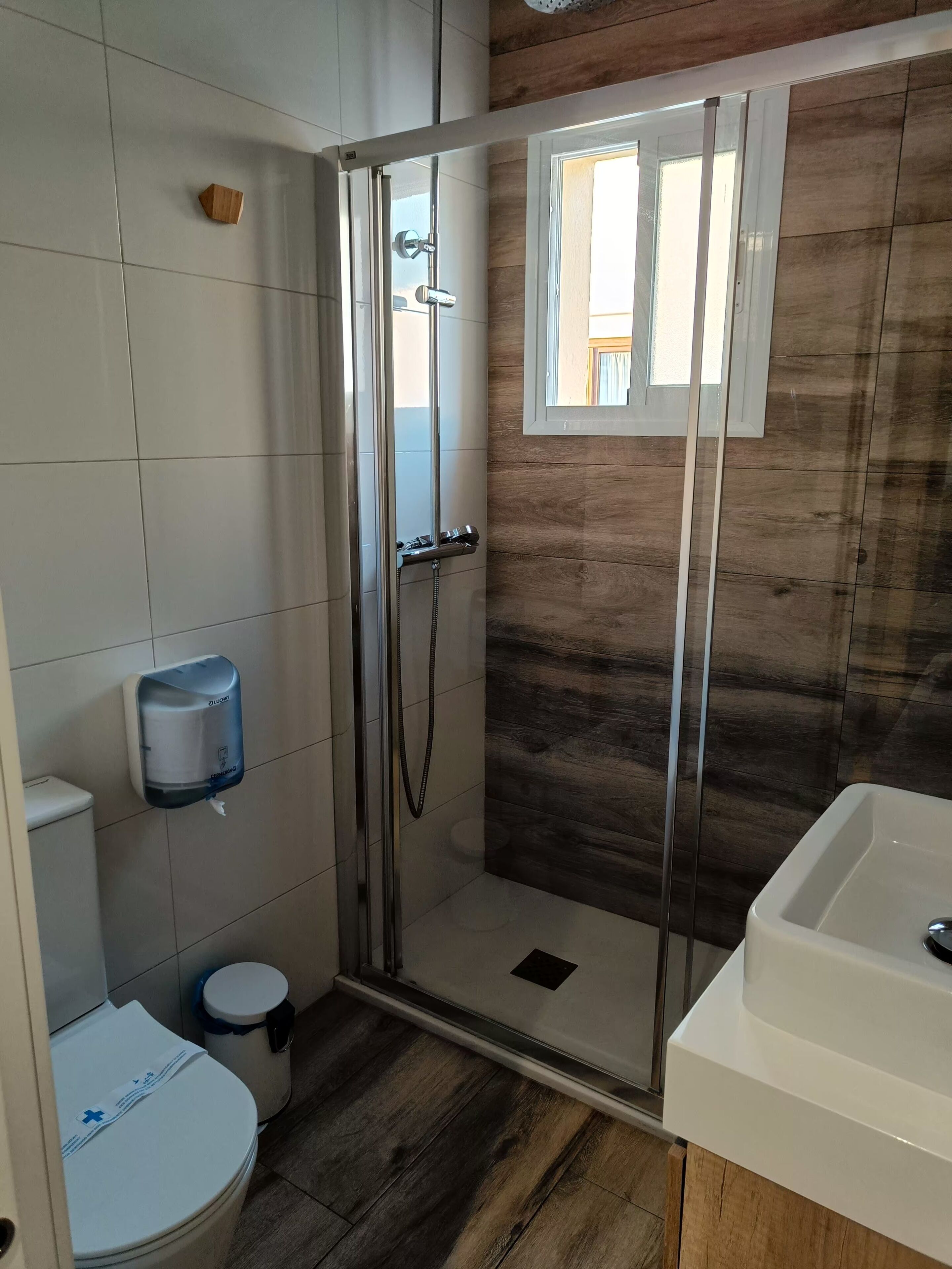 Een moderne badkamer met een douchecabine van glas, een toilet, een handdroger en een wastafel.