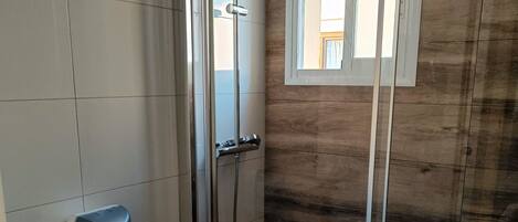 Een moderne badkamer met een douchecabine van glas, een toilet, een handdroger en een wastafel.
