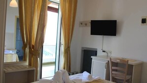 A hotel room with a bed, a desk, a chair, a television mounted on the wall, and a window with curtains. - Hotel al Bosco (Forio)