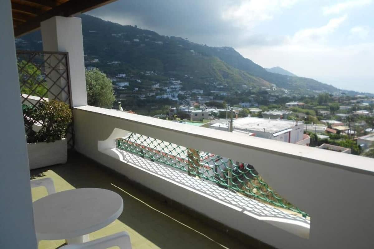 A balcony with a view of a town and mountains.