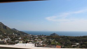 A coastal town with buildings and a mountain in the background. - Hotel al Bosco (Forio)