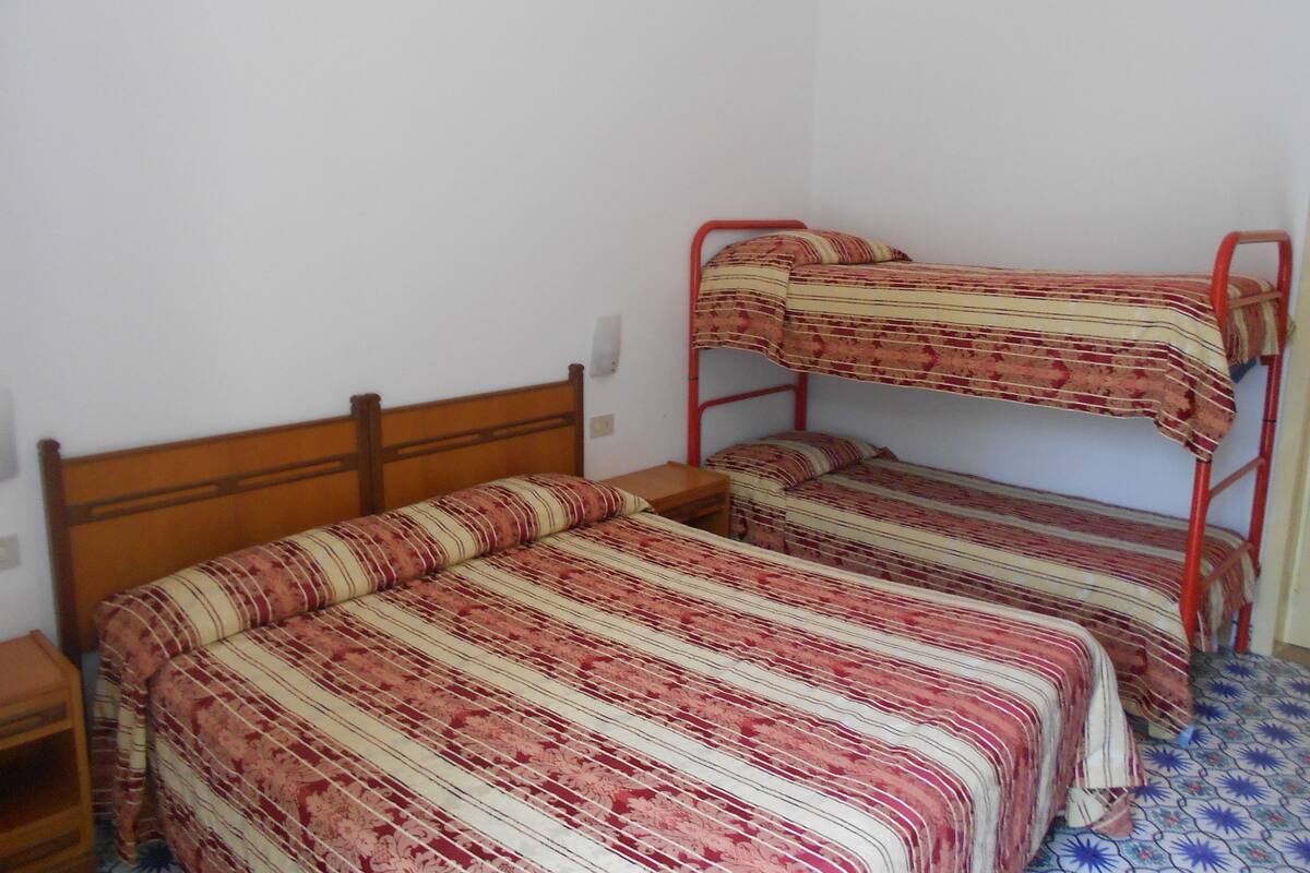 A bunk bed with striped bedding in a room with white walls and a wooden headboard.