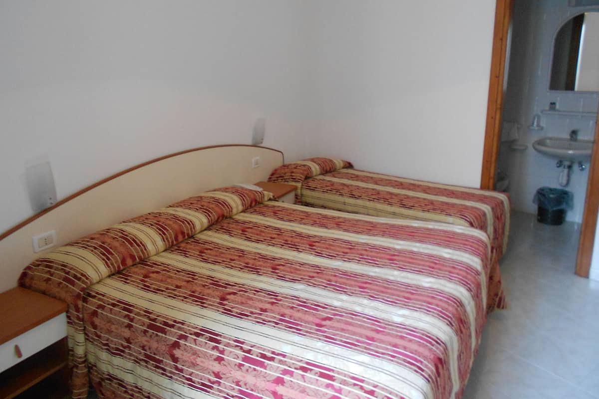 A small, single-room with a bed, a nightstand, and a bathroom visible through an open door.