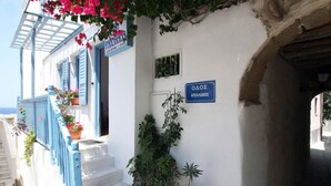 A white building with blue shutters and a sign reading "AOAO". - Panorama (Naxos)
