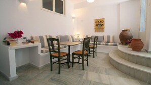 A dining area with a table and chairs, a sofa, and a decorative vase. - Panorama (Naxos)