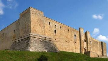 Un grande edificio storico in pietra, con un ingresso ben visibile e numerose finestre.