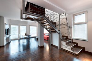 A modern interior with a spiral staircase, a dining area, and large windows.