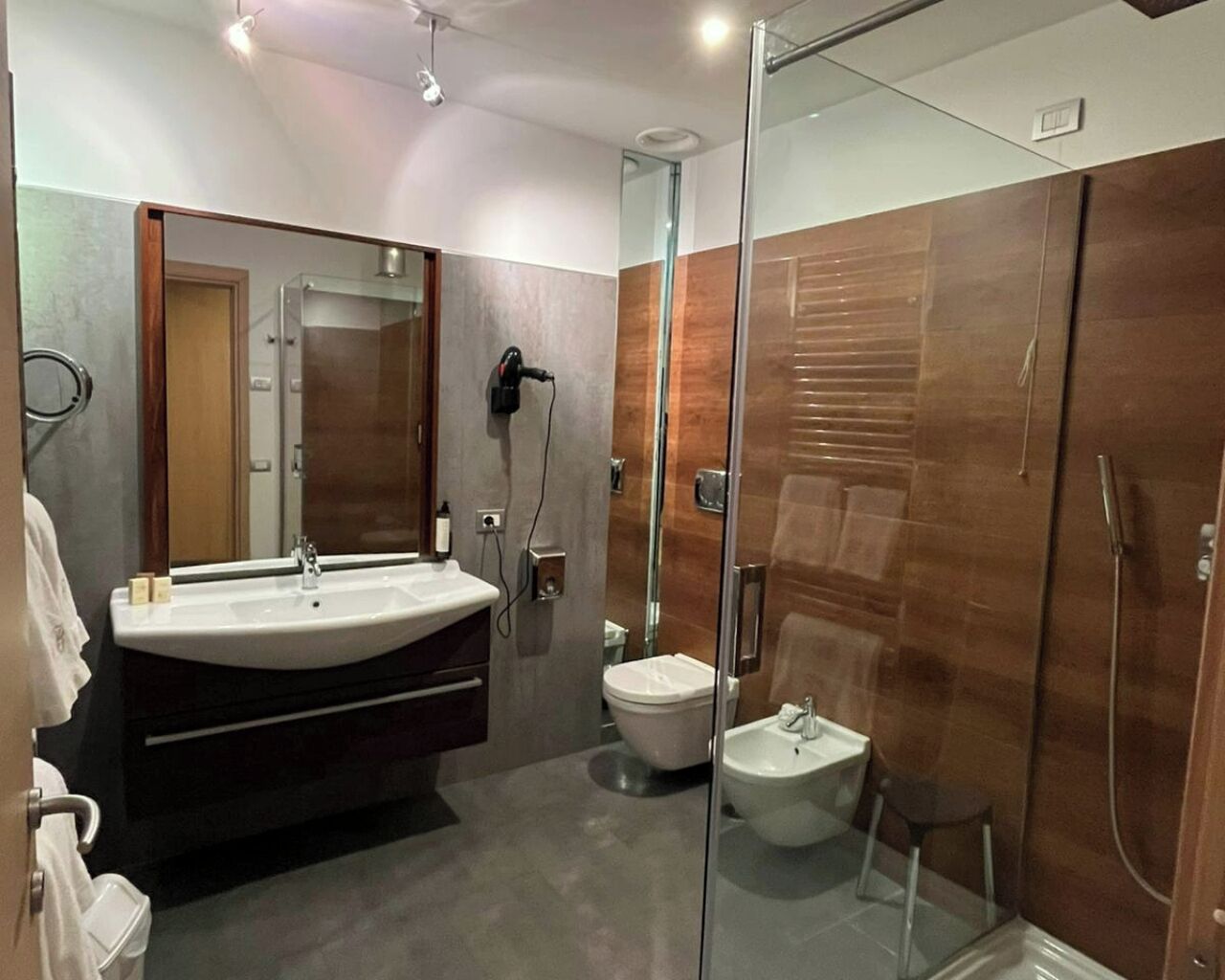 A modern bathroom with a glass-enclosed shower, a vanity with a sink, and a toilet.