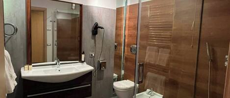 A modern bathroom with a glass-enclosed shower, a vanity with a sink, and a toilet.