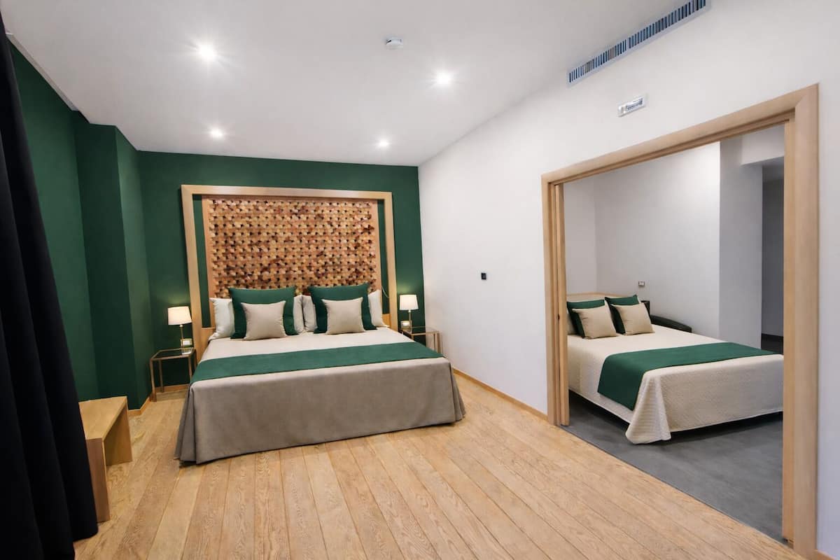 Een hotelkamer met twee bedden, een houten hoofdbord, een spiegel en een houten vloer.