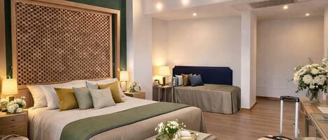 A spacious hotel room with a large bed, two bedside tables, a desk, and a suitcase.