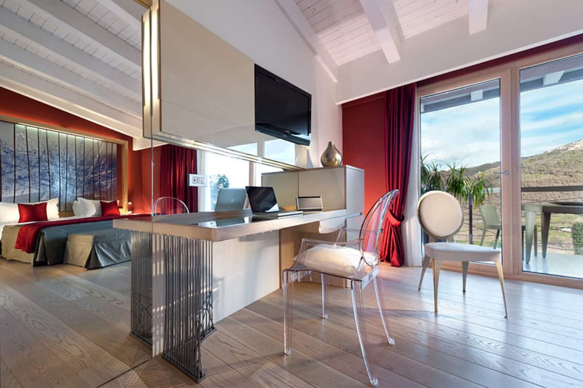 Een moderne woonkamer met een houten vloer, een zithoek, een eethoek met een tafel, en een groot raam met uitzicht op de omgeving.