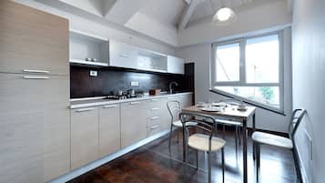 Une cuisine moderne avec des meubles de couleur bois clair, un revêtement mural foncé et un coin repas comprenant une table et des chaises.