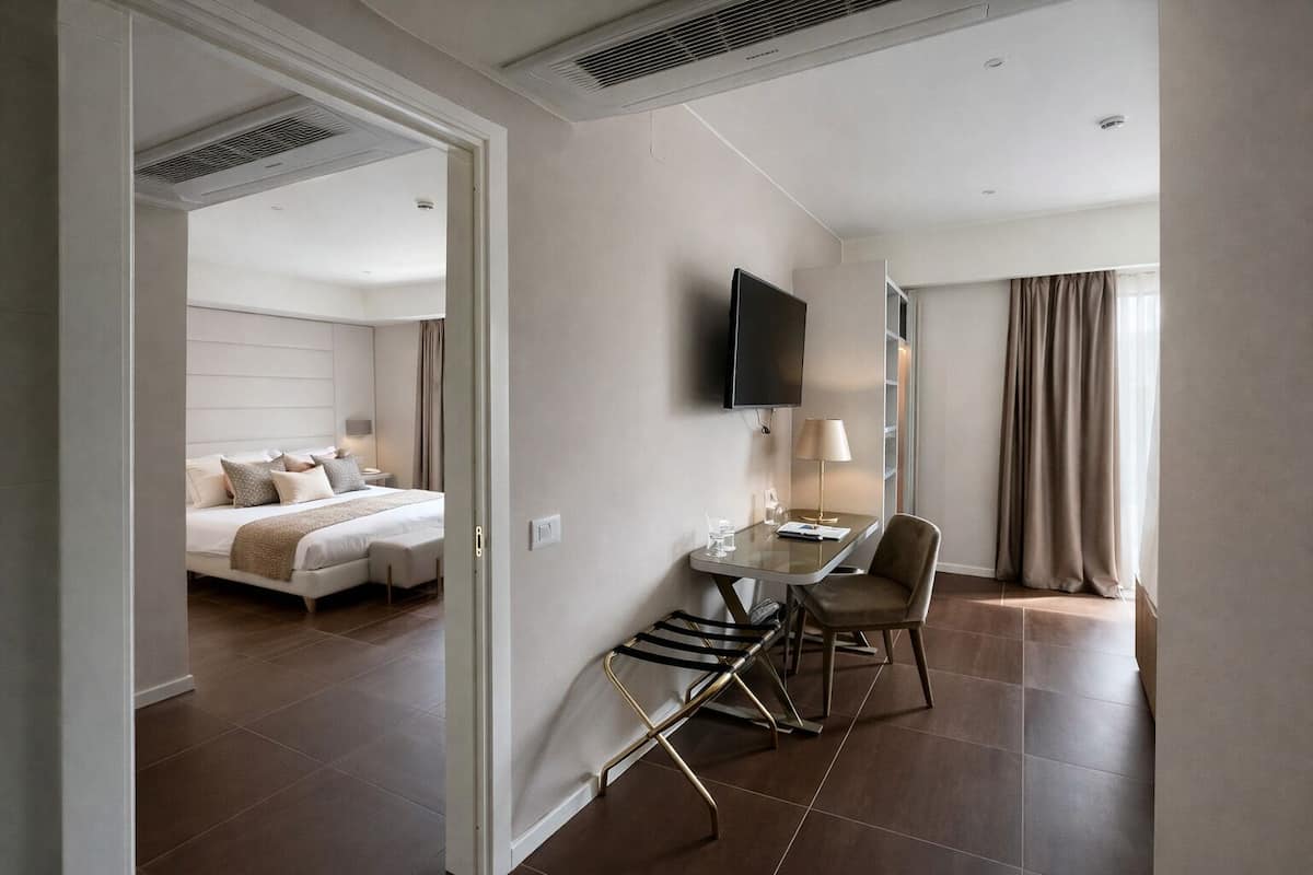 Een hotelkamer met een bed, een bureau met stoel, een televisie en een raam met gordijnen.