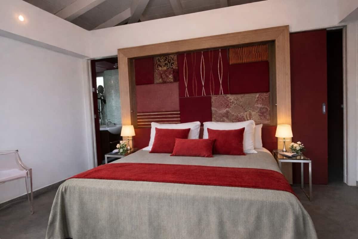 Een moderne slaapkamer met een groot bed, een houten hoofdbord en een rode accentmuur.