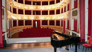 A grand theater with a central stage, multiple balconies, and a grand piano. - Hotel Bouganville (Picerno)