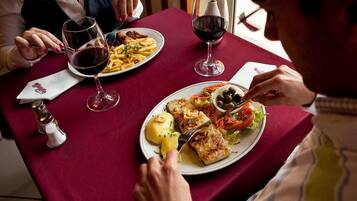 Un tavolo da pranzo con piatti di cibo, bicchieri di vino e un saliera.