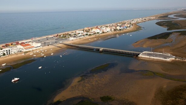 An aerial view of a coastal town with a long pier extending into the water, surrounded by buildings and boats. - Hospedaria Frangaria (Faro)