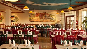 A restaurant with multiple tables and chairs, a mural on the wall, and hanging pendant lights. - Hospedaria Frangaria (Faro)