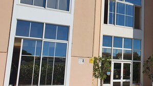 A building with multiple windows and a door, surrounded by potted plants. - Hospedaria Frangaria (Faro)