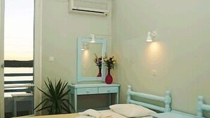 Un dormitorio con dos camas, una mesita de noche con un florero, un espejo y un equipo de aire acondicionado en la pared.