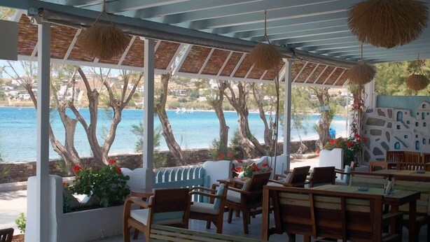 Un espacio de estar al aire libre cubierto con muebles de madera y vista al mar.