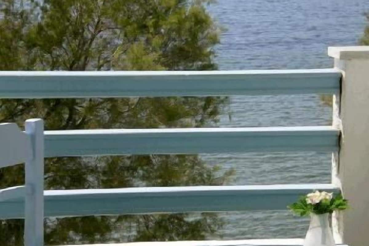 A balcony with a view of the sea and a sailboat in the distance.