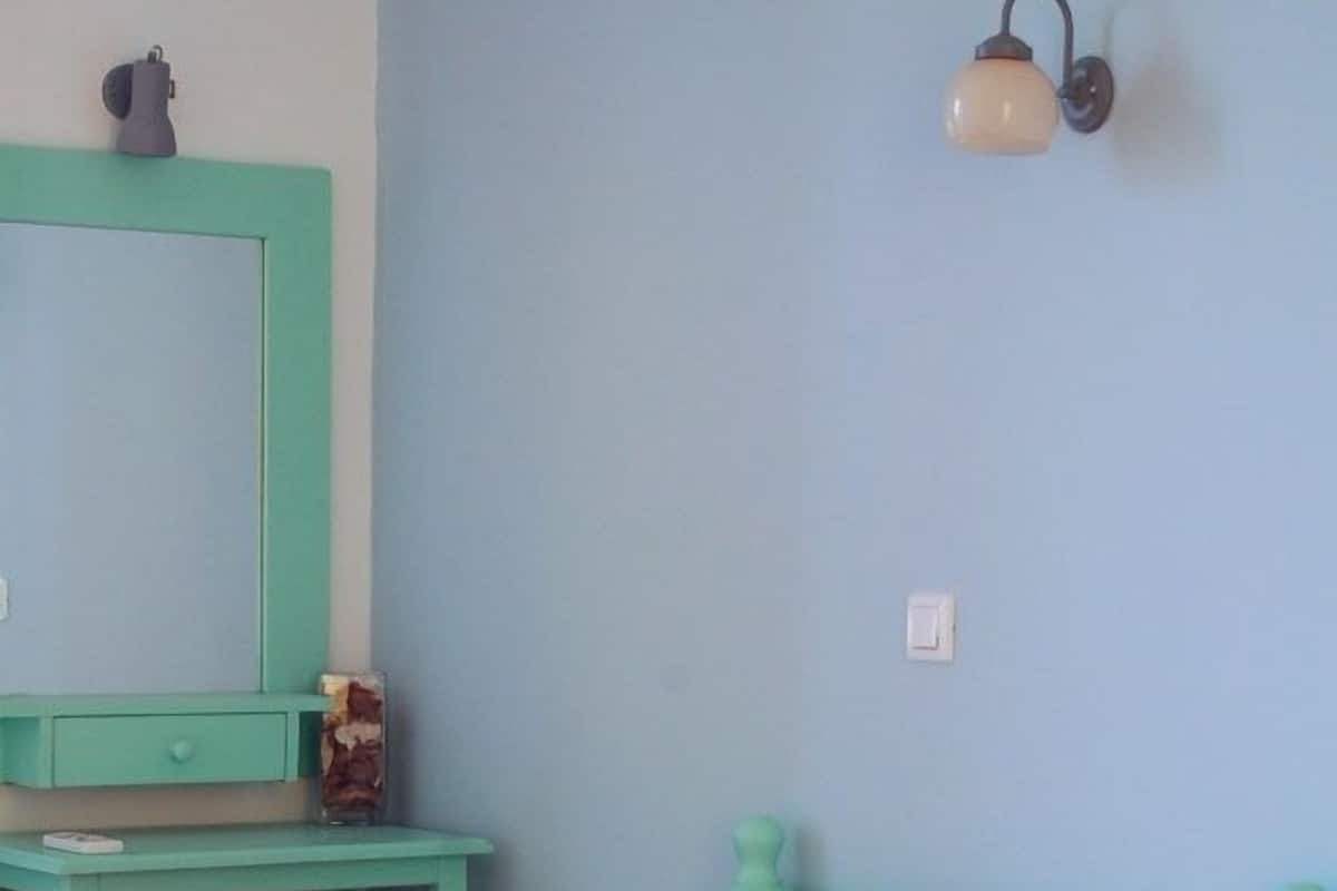 A room with two beds, a desk, and a wall-mounted light fixture.