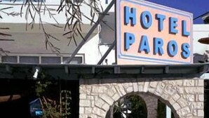Entrada de un hotel con un arco de piedra y un cartel que dice "HOTEL PAROS".
