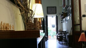 A hallway with a wooden counter displaying figurines, a lamp, and a door leading to an outdoor area with a table and chairs. - Casa Barbero Charme & Rooms (Catania)