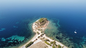 An aerial view of a small island with a sandy beach and clear blue waters. - Asia Apart Hotel (Kusadasi)