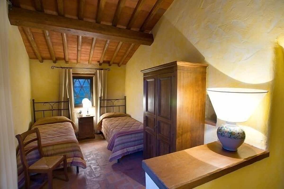 Un dormitorio con dos camas, un armario de madera, una mesita de noche y una lámpara.