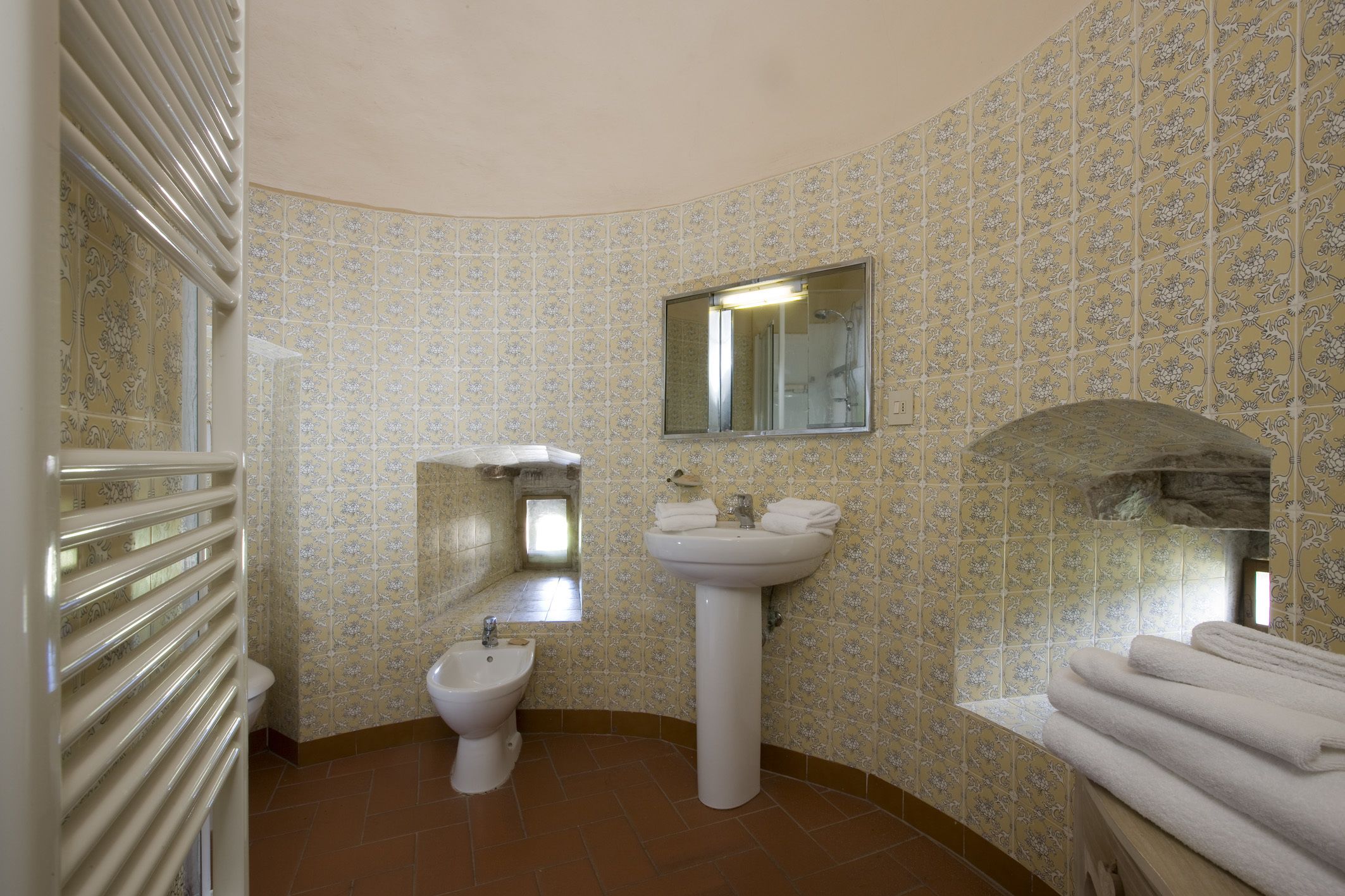 A bathroom with a bidet, sink, mirror, and towel rack.
