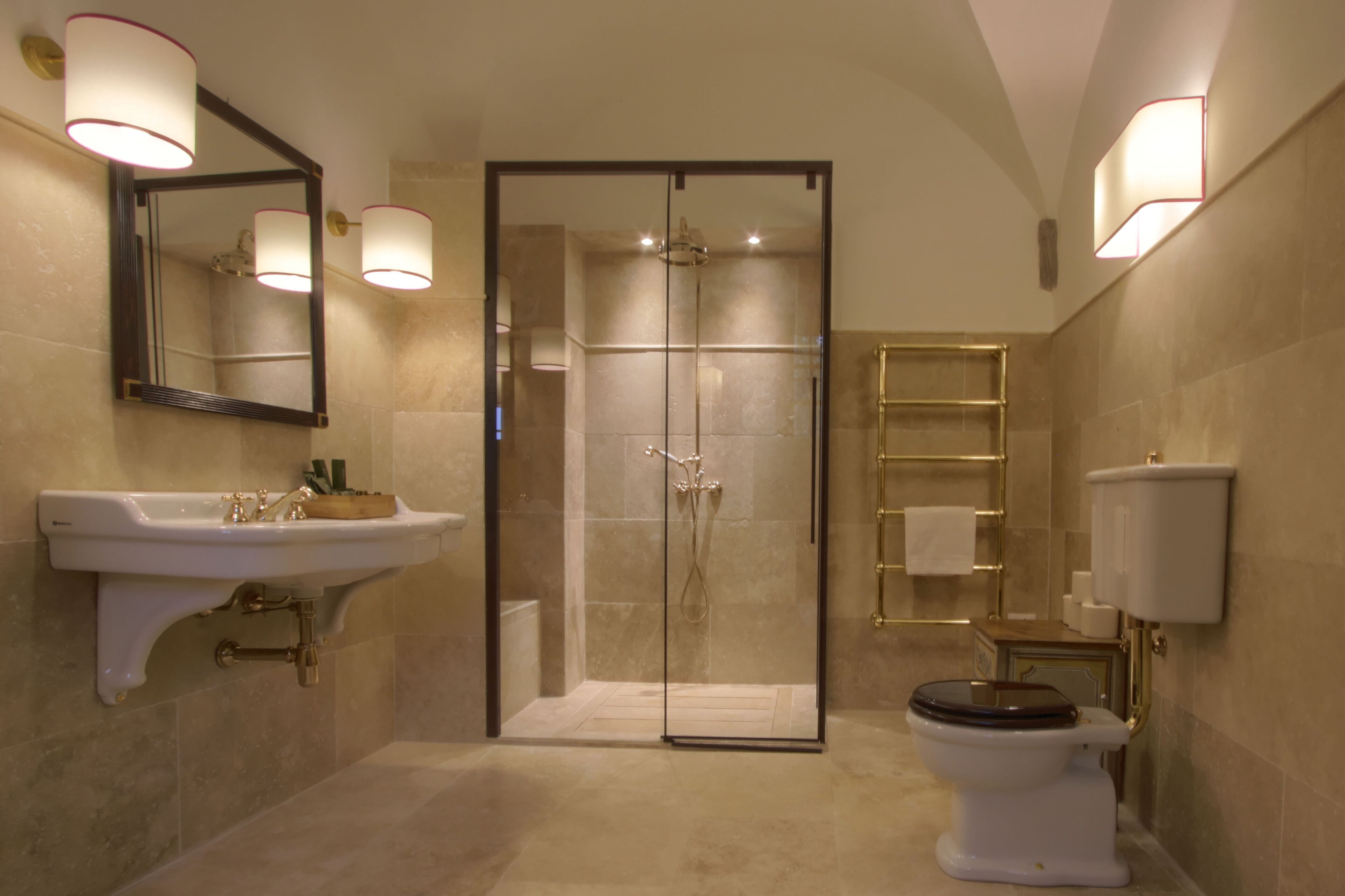 A modern bathroom with a glass-enclosed shower, a pedestal sink, and a toilet.
