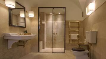 A modern bathroom with a glass-enclosed shower, a pedestal sink, and a toilet.