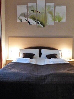 Una cama bien hecha con almohadas blancas y oscuras, una colcha acolchada y un cabecero.