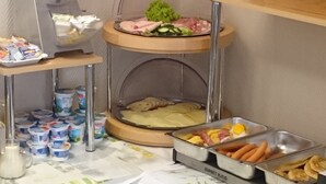 A buffet setup with various food items and condiments. - City Hotel Gotland (Berlin)