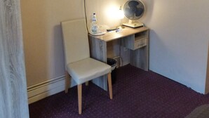 A small room with a desk, chair, TV, and a fan. - City Hotel Gotland (Berlin)