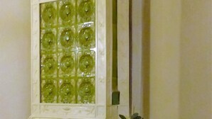 A white fireplace with green glass panels and a decorative top. - City Hotel Gotland (Berlin)