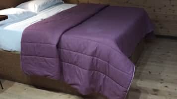 Una habitación de cabaña de madera con una cama, un edredón morado y un cartel en la pared.