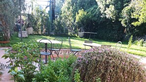 A garden area with a variety of plants and a seating area with tables and chairs.
