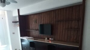 A bedroom with a bed, a TV mounted on a wooden wall, and a dresser.