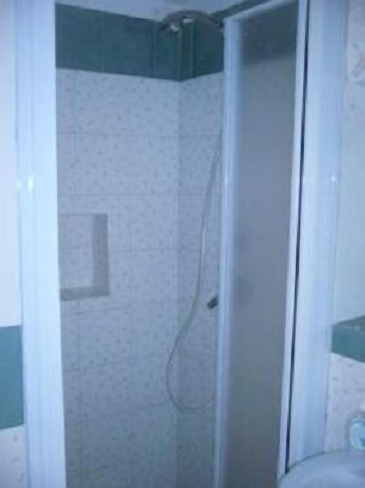 A small, enclosed shower area with a tiled wall and a door.