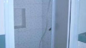 A small, enclosed shower area with a tiled wall and a door.