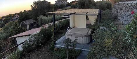 Een tuin met een jacuzzi, een pergola en een stenen muur.