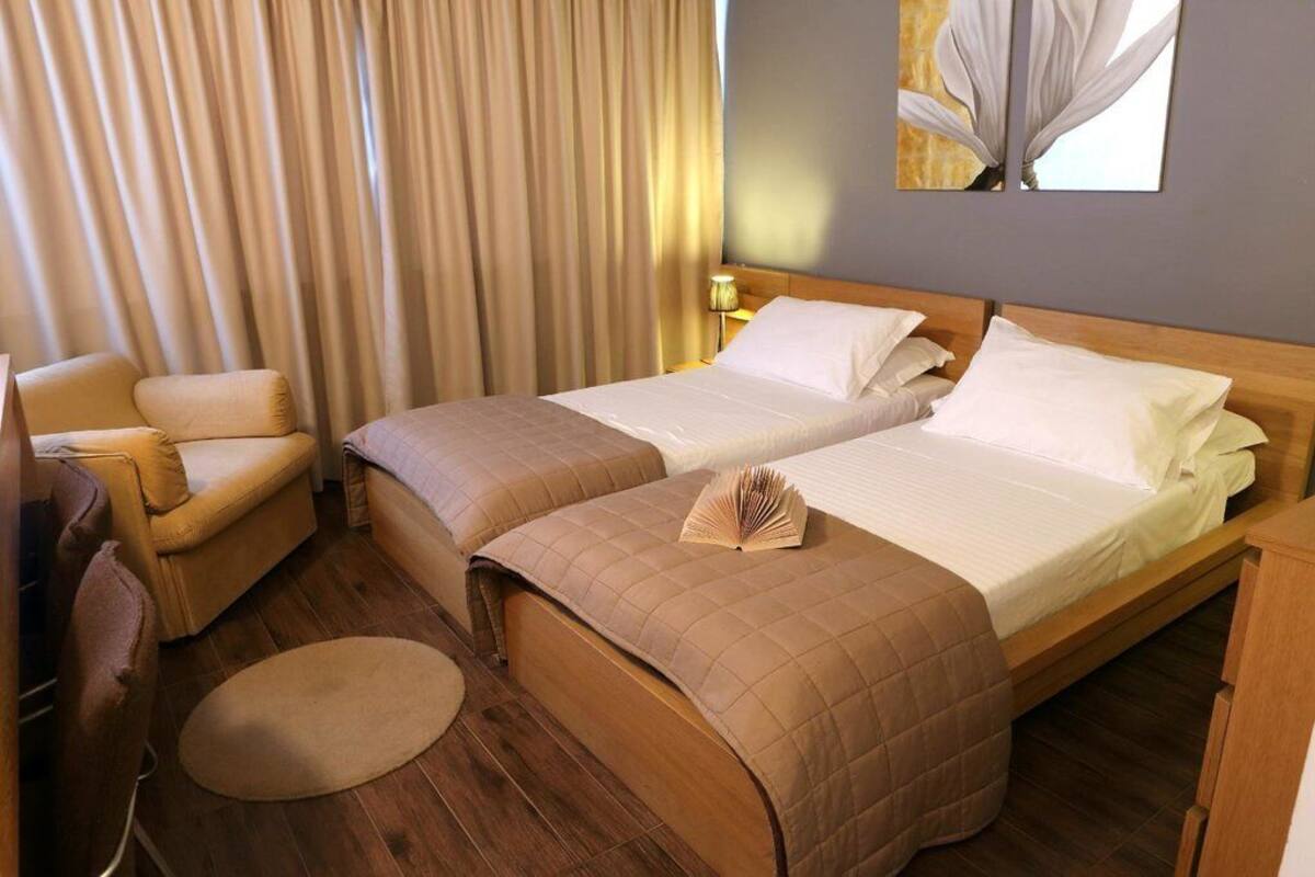 A hotel room with a bed, two chairs, a small round table, and a painting on the wall.